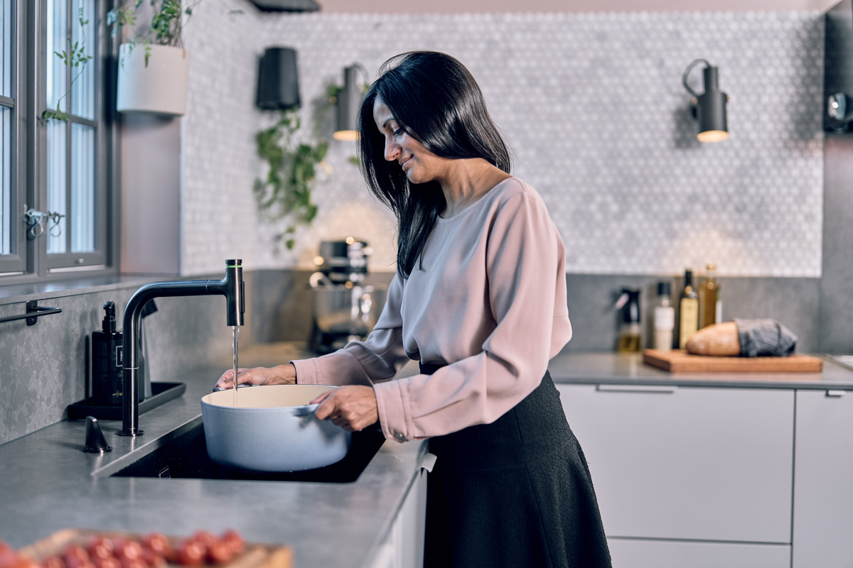 Kvinne ved kjøkkenbenken som tapper vann til en kjele